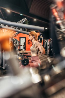 Güzel, genç, kızıl saçlı kadın geniş ve modern bir spor salonunda egzersiz yapıyor. İnsanlar ve eğlence konsepti.