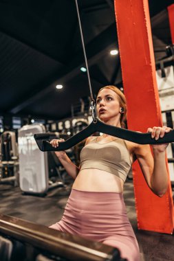 Güzel, genç, kızıl saçlı kadın geniş ve modern bir spor salonunda egzersiz yapıyor. İnsanlar ve eğlence konsepti.