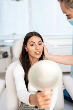 Güzellik kliniğindeki güzel ve mutlu esmer kadın. Kadın doktorla yüz estetiği hakkında konuşuyor..