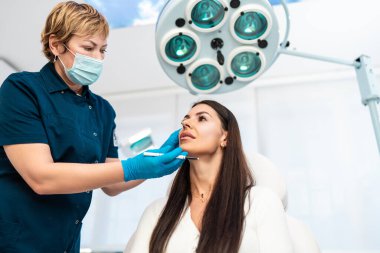 Güzellik kliniğindeki güzel ve mutlu esmer kadın. Kadın doktorla yüz estetiği hakkında konuşuyor..