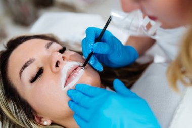 Professional permanent make up procedure. Tattoo lips makeup treatment in modern beauty salon.