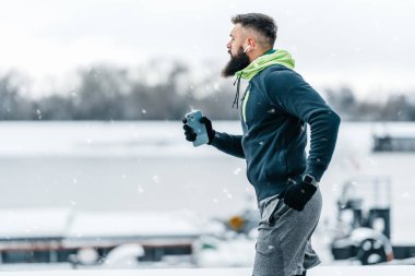 Çok soğuk ve karlı bir günde sakallı, koşan ve dışarıda egzersiz yapan yakışıklı orta yaşlı bir adam. Spor ve spor motivasyon teması.