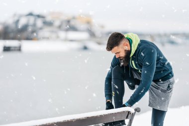 Çok soğuk ve karlı bir günde sakallı, koşan ve dışarıda egzersiz yapan yakışıklı orta yaşlı bir adam. Spor ve spor motivasyon teması.