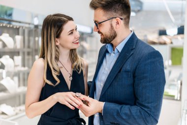 Modern kuyumcuda alışveriş yapan güzel bir çift. Pahalı bir yüzük ve bilezik takmış bir kadının elini yakın plan çek..