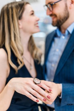 Modern kuyumcuda alışveriş yapan güzel bir çift. Pahalı bir yüzük ve bilezik takmış bir kadının elini yakın plan çek..