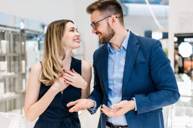 Modern kuyumcuda alışveriş yapan güzel bir çift. Genç bayan, harika bir kolye ve küpe deneyin. Moda tarzı ve zarafet konsepti.