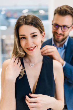 Modern kuyumcuda alışveriş yapan güzel bir çift. Genç bayan, harika bir kolye ve küpe deneyin. Moda tarzı ve zarafet konsepti.