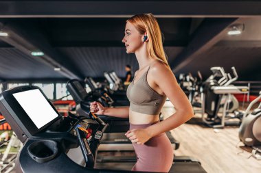 Güzel, genç, kızıl saçlı kadın geniş ve modern bir spor salonunda egzersiz yapıyor. İnsanlar ve eğlence konsepti.