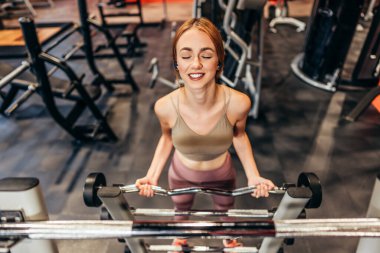 Güzel, genç, kızıl saçlı kadın geniş ve modern bir spor salonunda egzersiz yapıyor. İnsanlar ve eğlence konsepti.