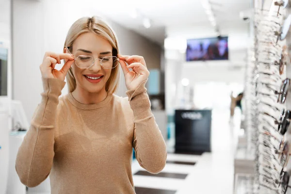 Modern optik mağazada gözlük çerçevesi seçen güzel ve şık bir kadın.. 