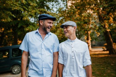 Yakışıklı ve mutlu baba ve genç oğlu şehir caddesinde yürüyorlar. Gülümsüyorlar ve birlikte konuşuyorlar..