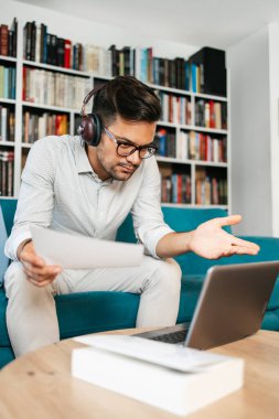 Genç, hoş görünümlü sanatçı stüdyo veya oturma odasında oturuyor, müzik dinliyor, dizüstü bilgisayarında çalışıyor, gülümsüyor ve bir sonraki başarılı projesini düşünüyor.. 