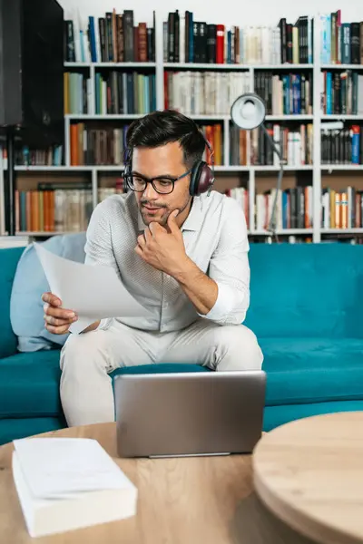 Genç, hoş görünümlü sanatçı stüdyo veya oturma odasında oturuyor, müzik dinliyor, dizüstü bilgisayarında çalışıyor, gülümsüyor ve bir sonraki başarılı projesini düşünüyor.. 