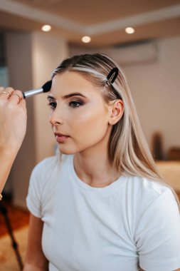 Makyaj süreci. Makyaj için makyaj yapan profesyonel bir sanatçı. Güzellik salonundaki güzel sarışın kadının portresini yakından çek.. 