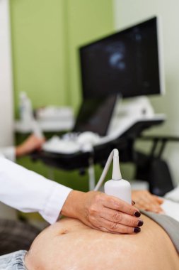 Female doctor doing ultrasound scan for a beautiful pregnant woman. Side view. Modern pregnancy  and healthcare concept.