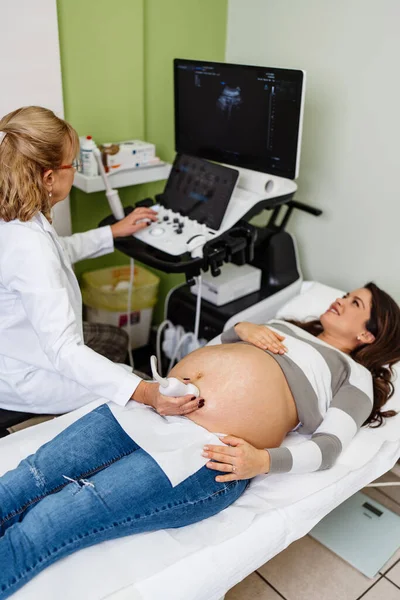 Female doctor doing ultrasound scan for a beautiful pregnant woman. Side view. Modern pregnancy  and healthcare concept.