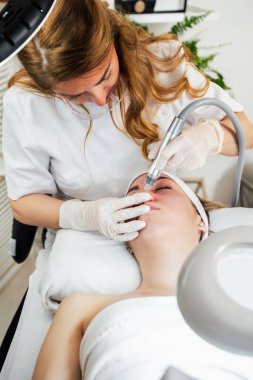 Genç bir kadın deri dökülmesi, yenilenmesi ve yüz derisinin sulanması için Hydra yüz tedavisi görüyor. Modern yüz hidro mikro cilt temizleme güzellik prosedürü. Hidra elektrikli süpürge.. 