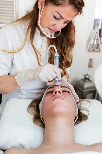 Young woman receiving modern radio-frequency face tightening treatment. Most popular non-invasive cosmetics procedure for removal of dermal lesions with radio waves. Radiowave surgery.