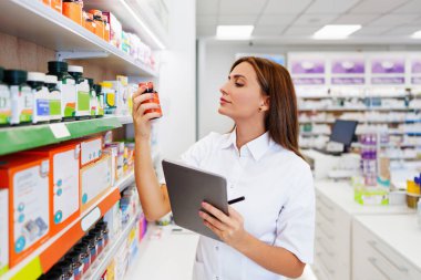 Güzel bir eczacı bir eczanede çalışıyor ve stok alımı yapıyor. Pozitif sağlık çalışanı portresi ya da iş yerinde çalışan bir kimyager..