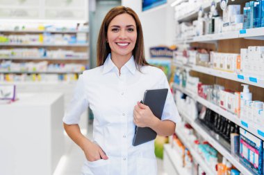 Güzel bir eczacı bir eczanede çalışıyor ve stok alımı yapıyor. Pozitif bir sağlık çalışanının portresi ya da iş yerindeki bir kimyagerin. Durup kameraya bakıyor..