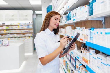 Güzel bir eczacı bir eczanede çalışıyor ve stok alımı yapıyor. Pozitif sağlık çalışanı portresi ya da iş yerinde çalışan bir kimyager..