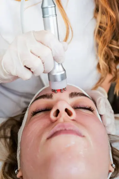 Young woman receiving modern radio-frequency face tightening treatment. Most popular non-invasive cosmetics procedure for removal of dermal lesions with radio waves. Radiowave surgery.