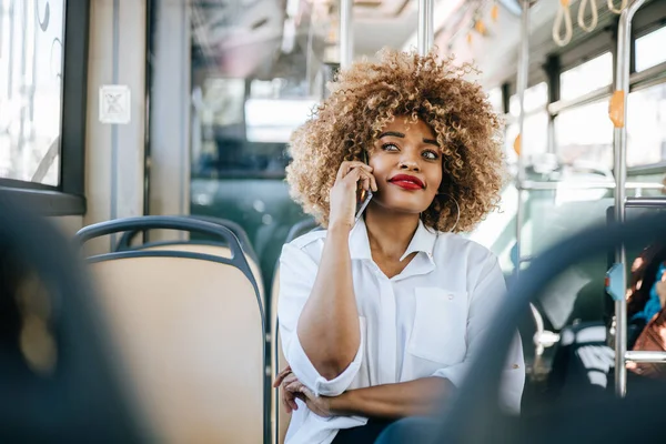 城市公共汽车上美丽而时髦的黑人妇女 当她用她的智能手机和别人交流时 她很开心 现代城市生活方式的概念 阳光灿烂的日子 — 图库照片