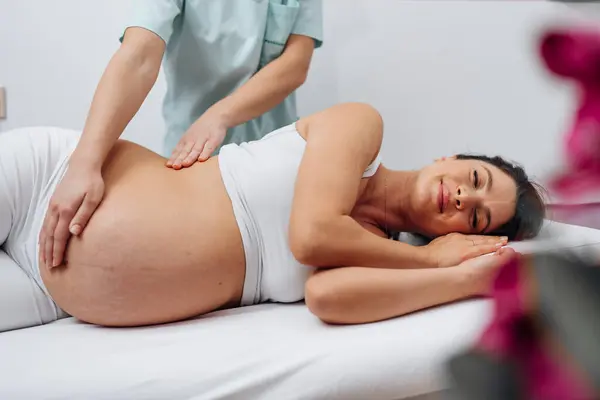 Beautiful Young Pregnant Woman Enjoying Relaxing Special Massage Treatment Maintaining 免版税图库图片
