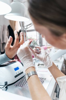 Modern bir güzellik salonunda çalışan profesyonel bir manikürcü. Kaplıcada manikür tedavisi gören tatmin olmuş bir bayan müşteri..