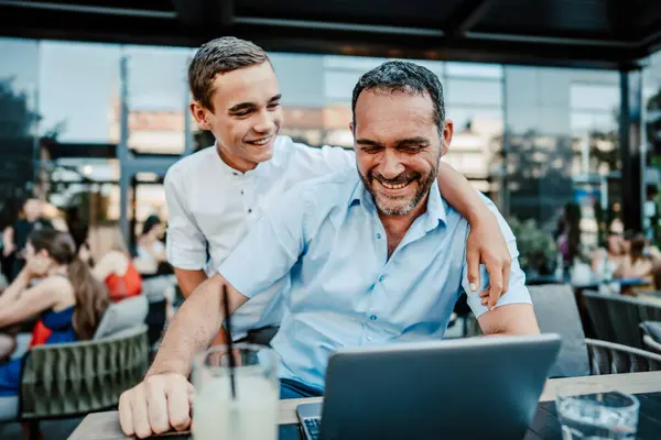 ハンサムで幸せな父親と10代の息子がレストランに座って話す ロイヤリティフリーのストック写真
