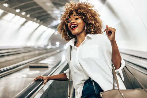 近代的な明るい地下鉄の駅への彼女の方法でエスカレーターに立って美しい黒人女性 公共交通機関と都市生活の概念 ローアングルショット ストック写真