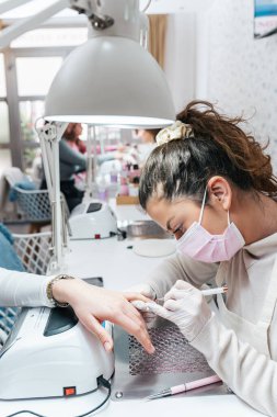 Modern bir güzellik salonunda çalışan profesyonel manikürcüler. Tatmin olmuş kadın müşteriler kaplıca merkezinde manikür tedavisi görüyor..
