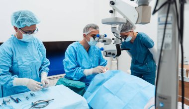 Yetenekli cerrah ve tıbbi ekibi yaşlı bir hastaya hassas bir göz ameliyatı yaparak en son tıbbi teknoloji ve ileri teknoloji ile görme yetisini geri kazandırıyor. Modern göz ameliyatı konsepti.