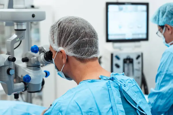 Der Erfahrene Chirurg Und Sein Medizinisches Team Führen Präzise Augenoperationen lizenzfreie Stockfotos