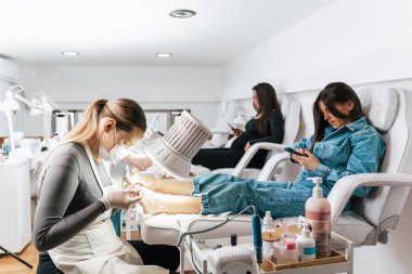 Modern bir tırnak güzellik stüdyosunda ya da kaplıcada çalışan bir grup profesyonel ayak doktoru. Tatmin olmuş müşteriler büyük bir ayak ve ayak tırnağı tedavisiyle rahatlıyor ve eğleniyorlar.. 