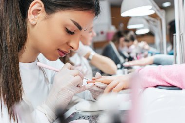 Modern bir güzellik salonunda çalışan profesyonel manikürcüler. Tatmin olmuş kadın müşteriler kaplıca merkezinde manikür tedavisi görüyor..