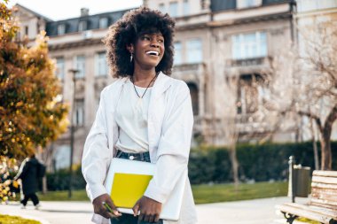 Güzel ve mutlu siyah kız öğrenci fakülte sınavına çalışırken kampüste eğleniyor..