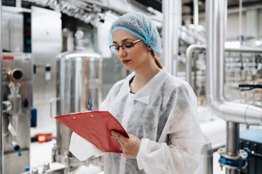 Tıbbi malzeme araştırma ve üretim fabrikasında çalışan ve sevkiyattan önce damıtılmış su kutularını kontrol eden koruyucu işçi. Denetim kalite denetimi. 