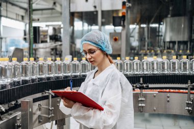 Tıbbi malzeme araştırma ve üretim fabrikasında çalışan ve sevkiyattan önce damıtılmış su kutularını kontrol eden koruyucu işçi. Denetim kalite denetimi. 