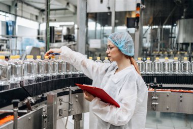 Tıbbi malzeme araştırma ve üretim fabrikasında çalışan ve sevkiyattan önce damıtılmış su kutularını kontrol eden koruyucu işçi. Denetim kalite denetimi. 