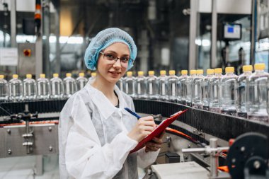 Tıbbi malzeme araştırma ve üretim fabrikasında çalışan ve sevkiyattan önce damıtılmış su kutularını kontrol eden koruyucu işçi. Denetim kalite denetimi. 