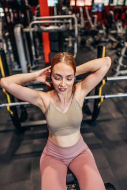 Güzel, genç, kızıl saçlı kadın geniş ve modern bir spor salonunda egzersiz yapıyor. İnsanlar ve eğlence konsepti.