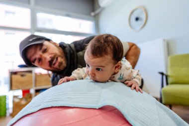 Sevimli kız, uzman bir çocuk spor salonunda veya oyun alanında uzman bir terapistle fizik tedavi seanslarından hoşlanıyor..