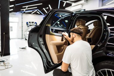 A man cleaning luxury car interior with microfiber cloth, car detailing or valeting concept. Selective focus. clipart