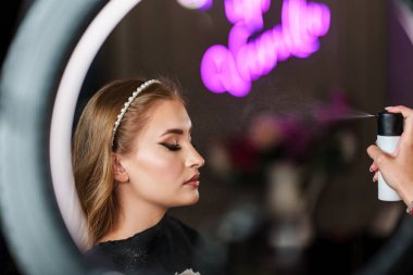 Profesyonel güzellik uzmanı güzel genç bir kadının yüzüne makyaj yapıyor. Muhteşem bir kadın modelle profesyonel makyaj stüdyosu çalışması..