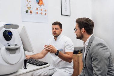 Çekici erkek doktor göz doktoru modern klinikteki yakışıklı orta yaşlı adamın görüşünü kontrol ediyor. Göz hekimliği kliniğinde doktor ve hasta kontrolü sırasında.. 