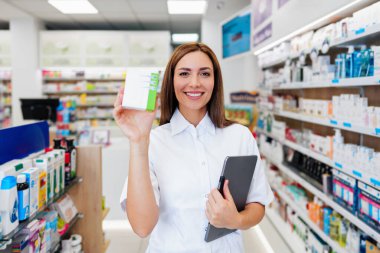 Güzel bir eczacı bir eczanede çalışıyor ve stok alımı yapıyor. Pozitif bir sağlık çalışanının portresi ya da iş yerindeki bir kimyagerin. Durup kameraya bakıyor..