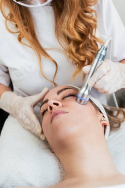 Güzel ve çekici genç bir kadın serumla profesyonel cilt bakımı görüyor. Modern ve popüler cilt bakımı kavramı.