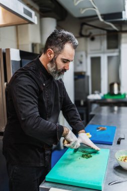 Yakışıklı sakallı profesyonel şef restoran mutfağında çalışıyor. O, balık ve deniz ürünleriyle sağlıklı lezzetli yemekler hazırlar..