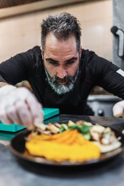 Yakışıklı sakallı profesyonel şef restoran mutfağında çalışıyor. O, balık ve deniz ürünleriyle sağlıklı lezzetli yemekler hazırlar..